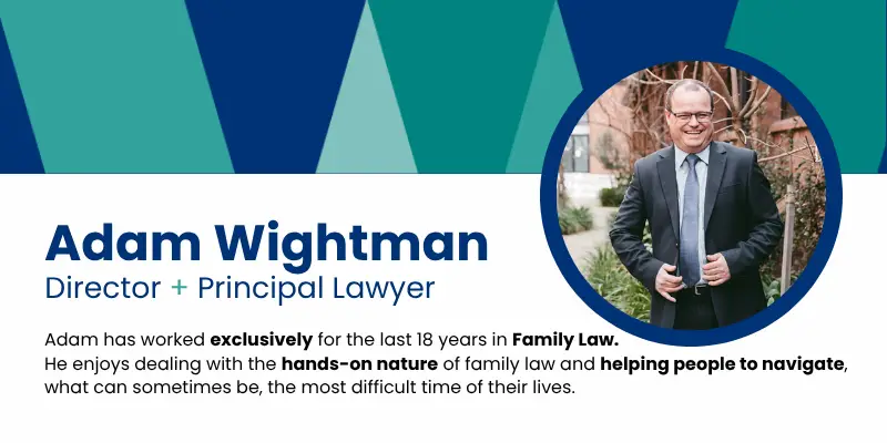 Pictured, Adam Wightman wearing a dark blue suit and buttoning up the middle button with a big smile on his face.
