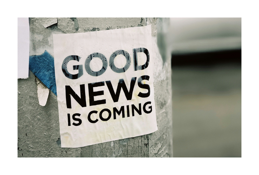Pictured, an electricity pole that has been showered in paper advertising, specifically, one that is on white paper, black block writing that says "GOOD NEWS IS COMING"